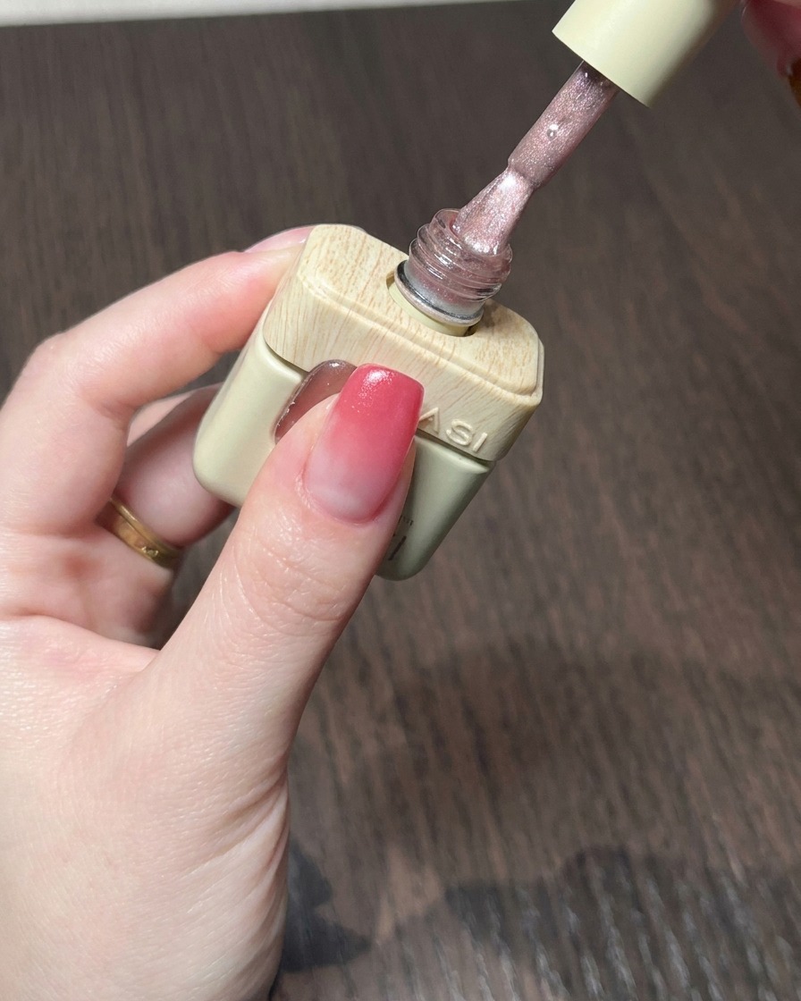 Pędzelek nakładający mieniący się żel cat eye w kolorze nude pink na bazę z czerwonym gradientem.