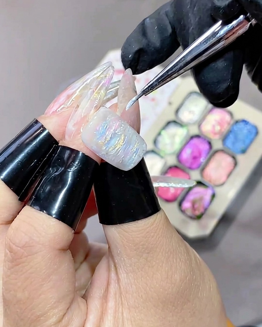 Pędzelek z cienką końcówką nakładający biały, rozświetlający żel na teksturowaną powierzchnię żelowego manicure.