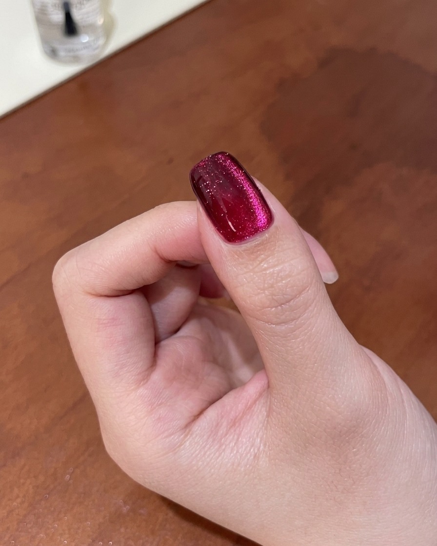 Zbliżenie na paznokieć pokazujące magnetyczny blask wygładzany w głęboki, gradientowy efekt cat-eye za pomocą magnesu.