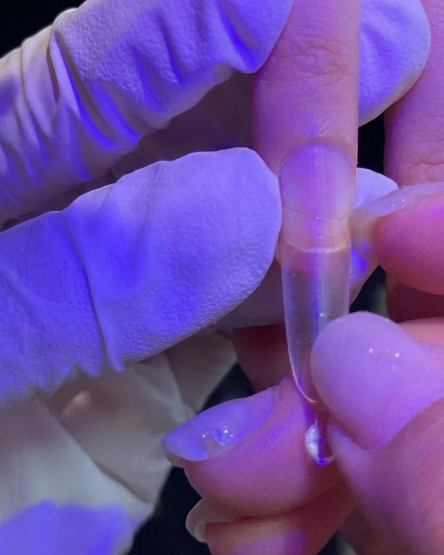 Dłoń dociskająca przezroczysty tips do naturalnego paznokcia.