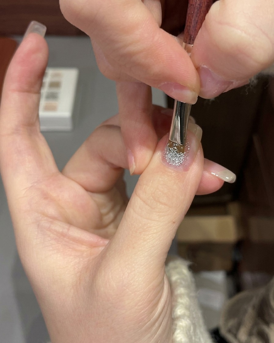 Dłoń umieszczona pod profesjonalną lampą UV/LED utwardzającą manicure żelowy.