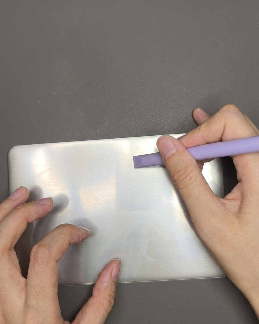 Plastikowa zdrapka przesuwająca się po płytce do stempli, usuwająca nadmiar białego lakieru.