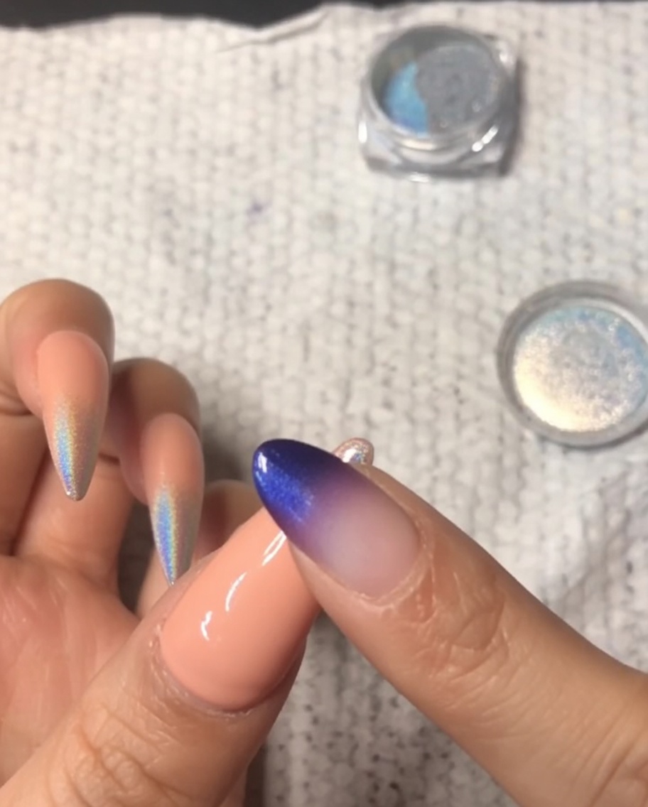 Zbliżenie na palec wcierający holograficzny pyłek chromowy w końcówkę małego paznokcia, tworząc gradient ombre.