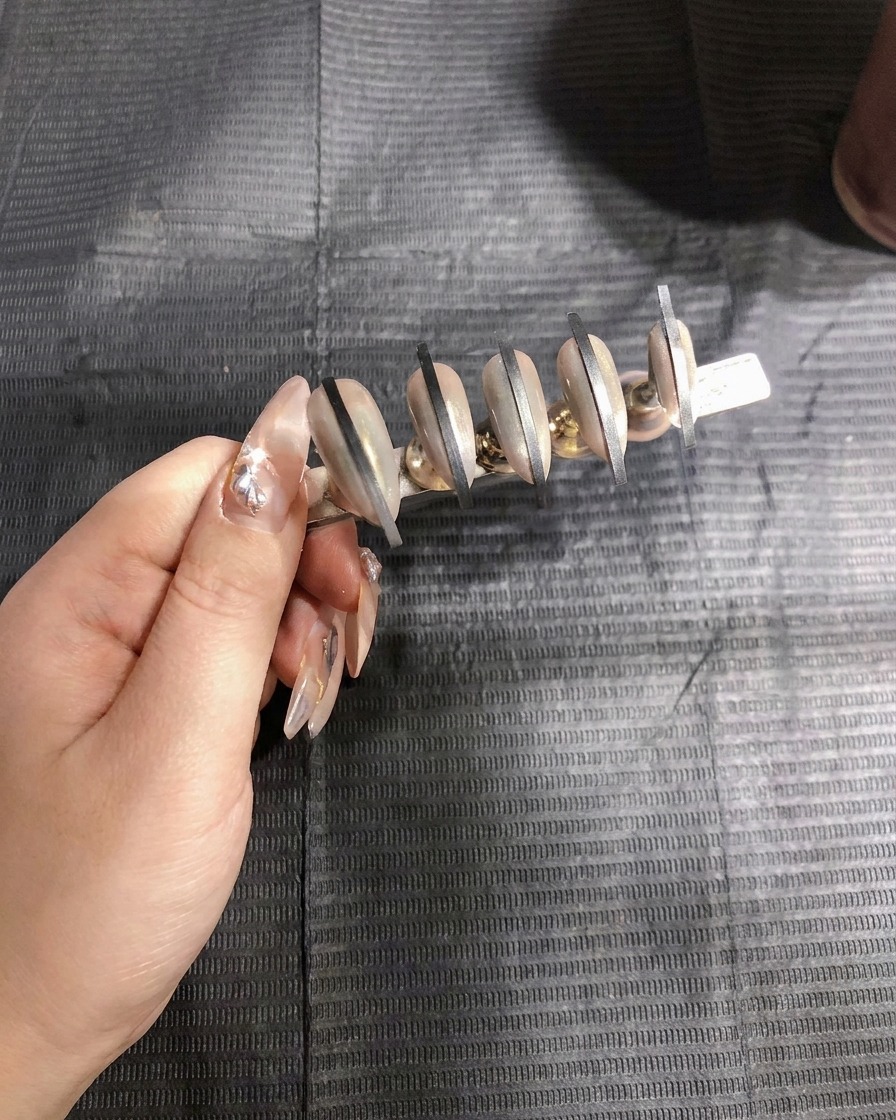Pistolet airbrush aplikujący pierwszą warstwę białego spray gelu na drugi zestaw paznokci.