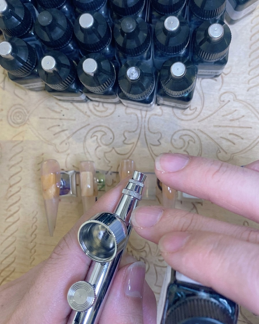 Zbliżenie na dłonie umieszczone w profesjonalnej lampie UV/LED z widocznym fioletowym światłem, utwardzające manicure.