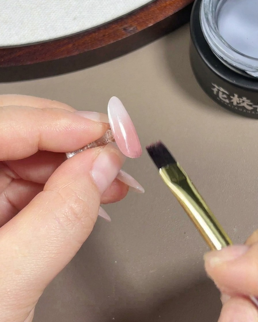 Pędzelek do żelu nakładający przezroczysty, błyszczący top coat na gotowy różowo-biały gradient z wykończeniem aurora.
