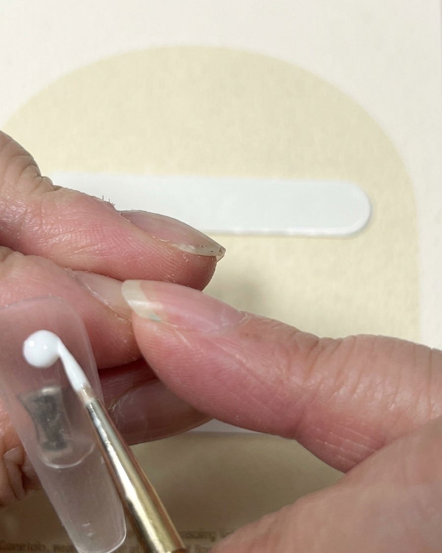 Pędzelek typu liner przeciągający biały żel z punktu środkowego, tworząc kształt pąka róży.