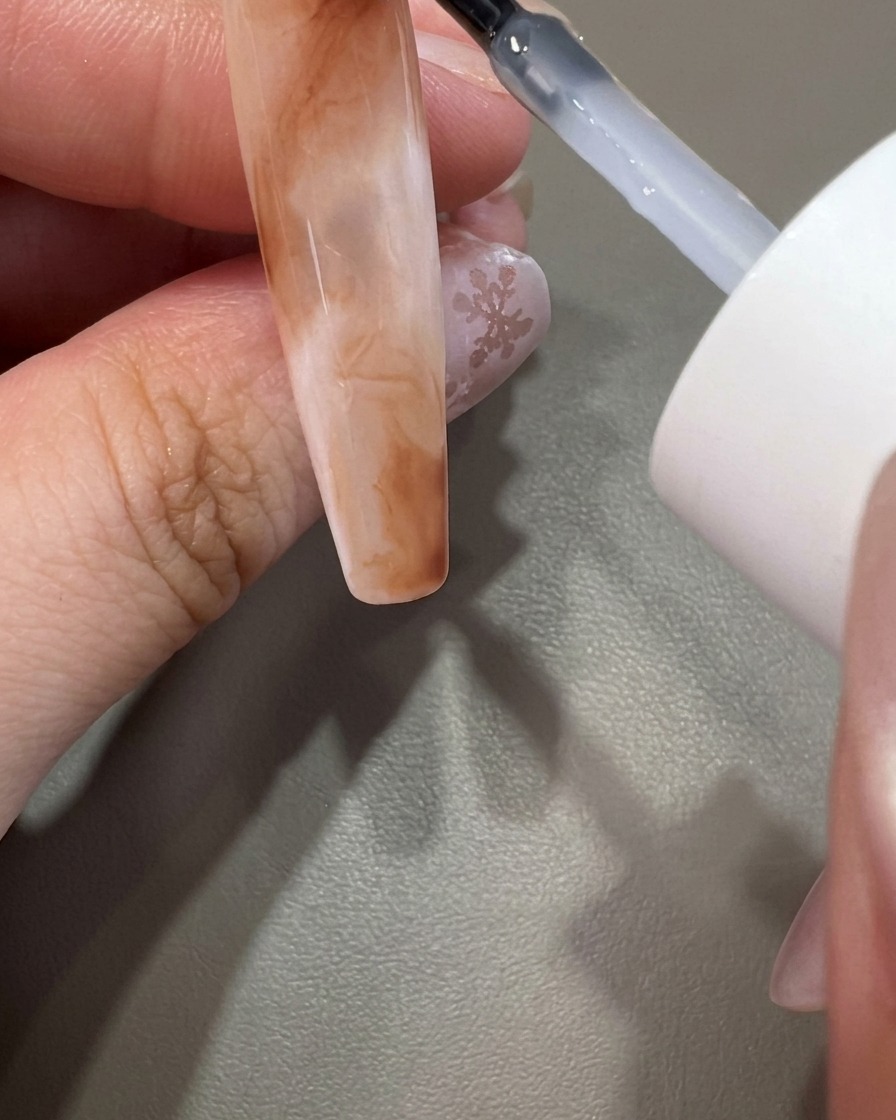Pędzelek nakładający nabłyszczający top coat na gotowy wzór.