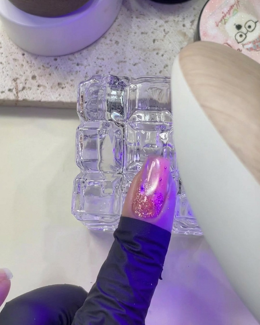 Dłoń umieszczająca paznokieć pod fioletowym światłem lampy UV/LED do utwardzania.