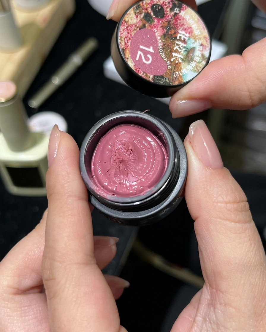 Otwarty słoiczek różowego lakieru magnetycznego cat-eye o konsystencji gęstego żelu.