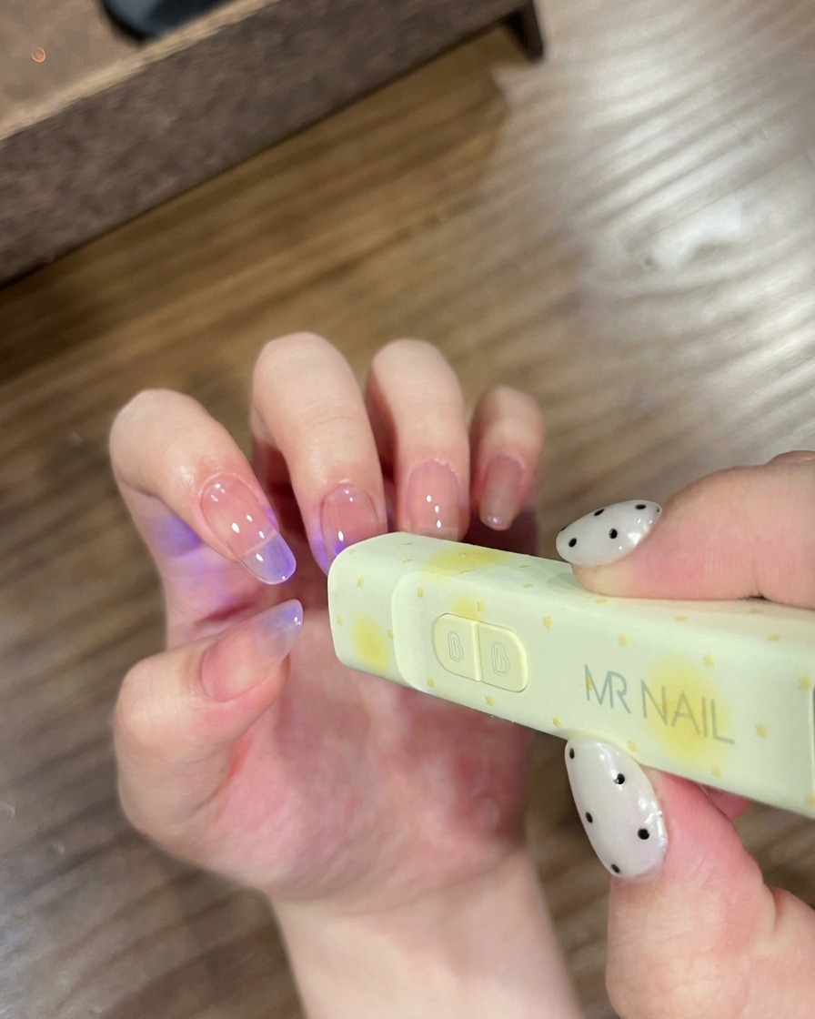 Paznokcie umieszczone pod małą lampą UV marki MR NAIL w celu utwardzenia.