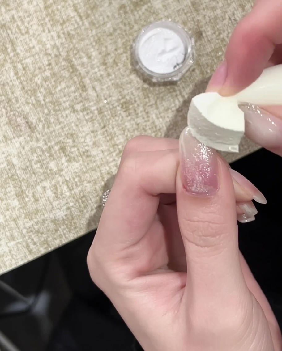 Pędzelek nakładający końcowy błyszczący top coat na paznokieć wykończony złotym efektem chrome.