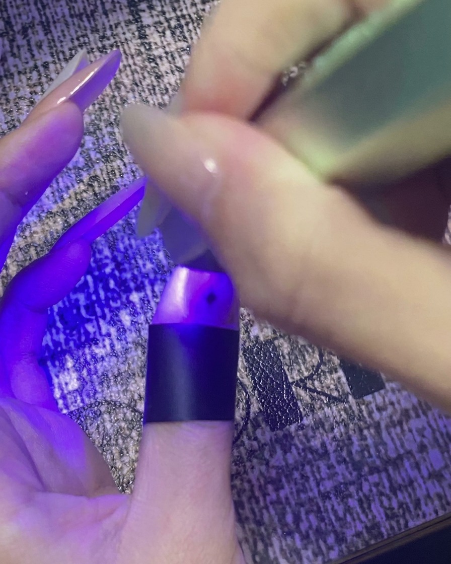 Kciuk ze zdobieniem w gwiazdki utwardzany pod fioletowym światłem małej lampy UV/LED.