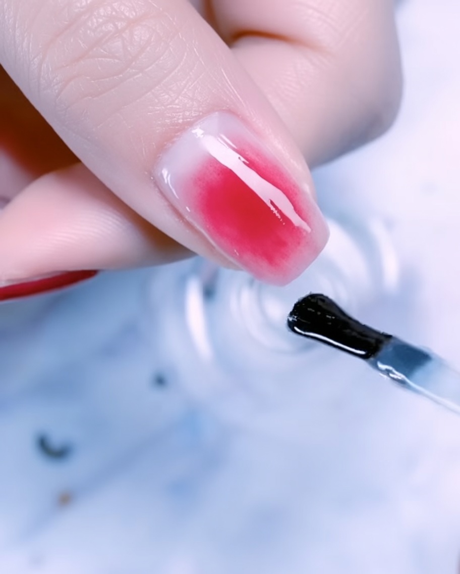 Zbliżenie na paznokieć kciuka ozdobiony folią, metalowym drucikiem i perełkami na gradiencie rose gold.