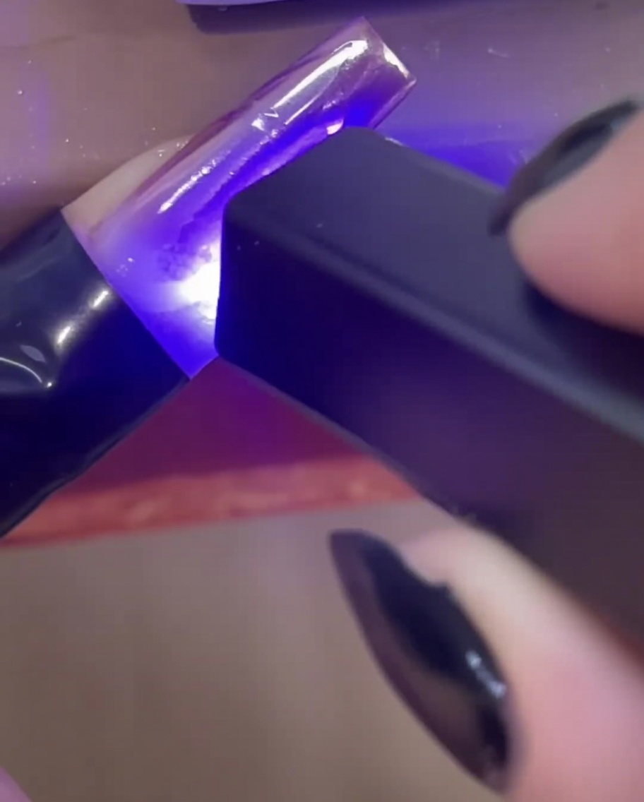 Mini, ręczna lampa UV/LED utwardzająca przezroczyste linie z żelu budującego 3D na przedłużonym paznokciu.