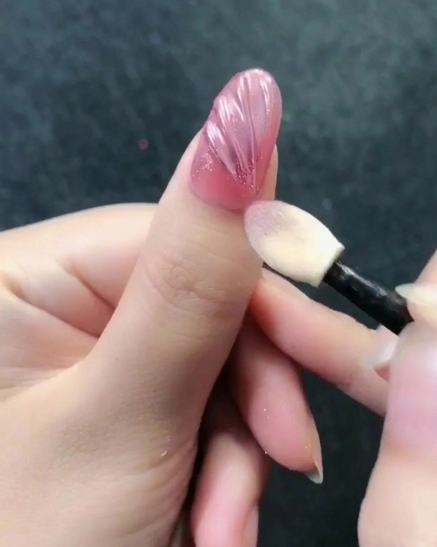 Aplikator do cieni wcierający pyłek rose gold w strukturalną powierzchnię paznokcia.