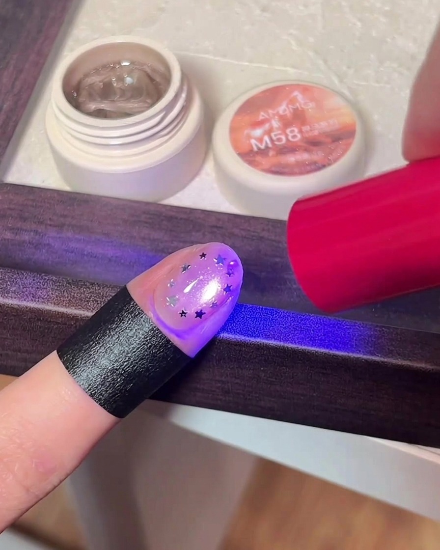 Paznokieć z gwiazdkami utwardzany pod fioletowym światłem lampy UV/LED.