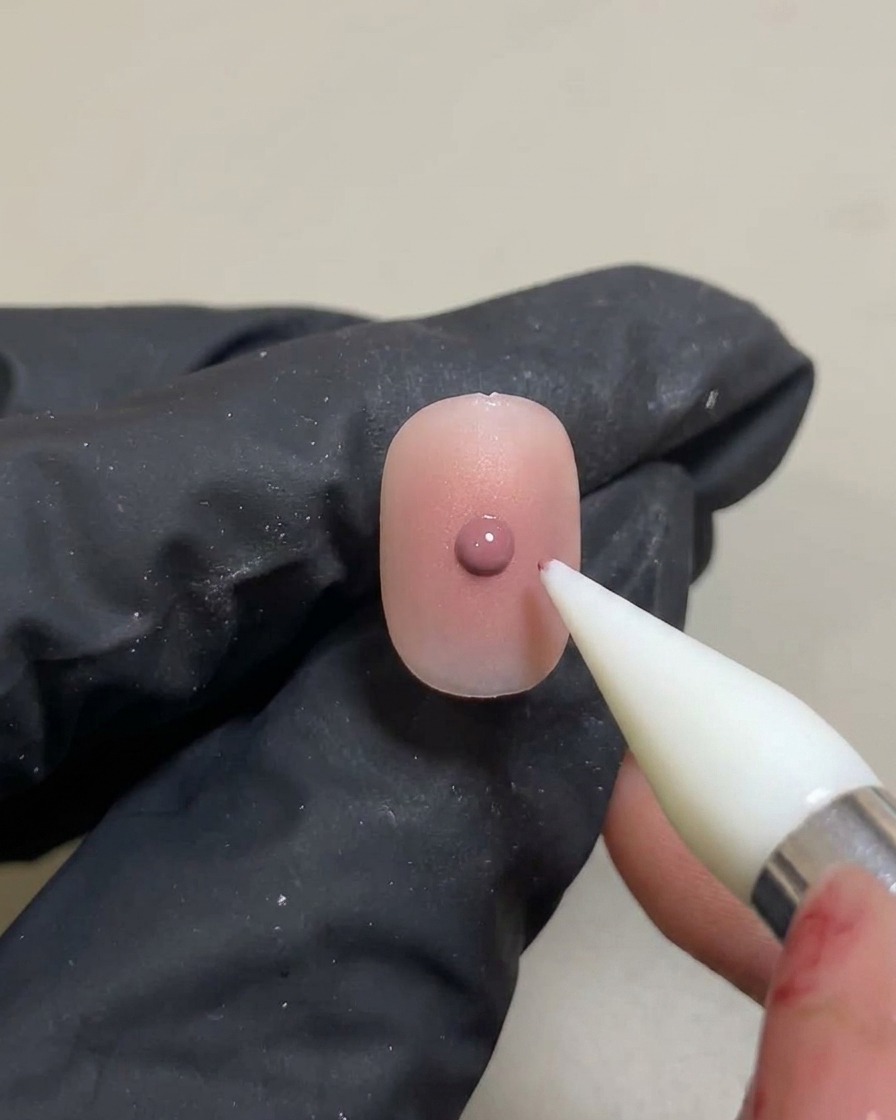 Silikonowe narzędzie nakładające małą, skoncentrowaną kropkę różowego żelu na wcześniej utwardzony gradient blush.