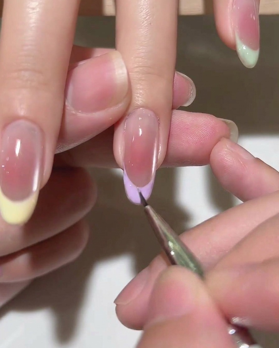 Pędzelek nakładający warstwę nabłyszczającego top coatu na gotowy french manicure.
