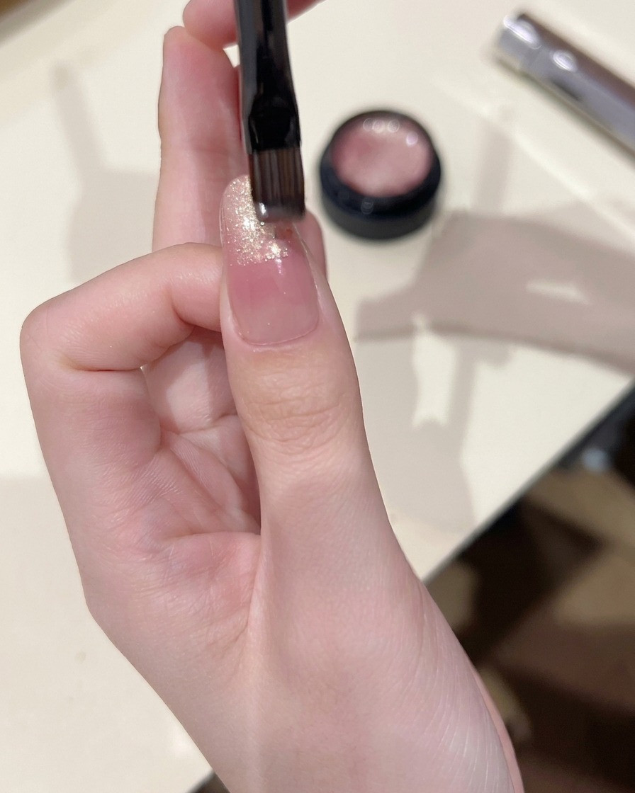 Mały pędzelek nakładający żel cat eye na końcówkę paznokcia, lekko blendując go w dół.