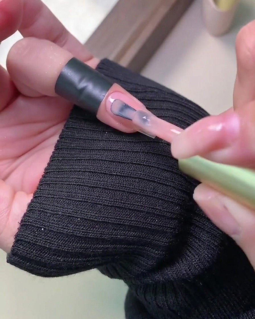 Zbliżenie pokazujące drugą warstwę kolorowego lakieru żelowego nakładaną płynnie na utwardzoną wcześniej warstwę.