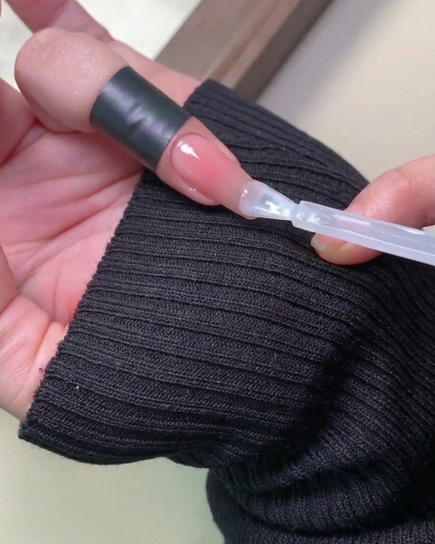 Dłoń z gotowym manicure wewnątrz lampy UV/LED, z paznokciami oświetlonymi światłem.