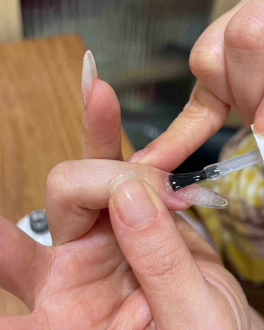 Pędzelek nakładający przezroczysty, nabłyszczający top coat na teksturowany paznokieć cat-eye.