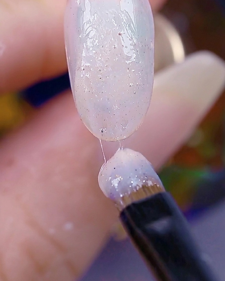 Pędzelek do paznokci nakładający drugą warstwę żelu sugar gel, powierzchnia paznokcia wygląda na chropowatą i gotową do utwardzenia.