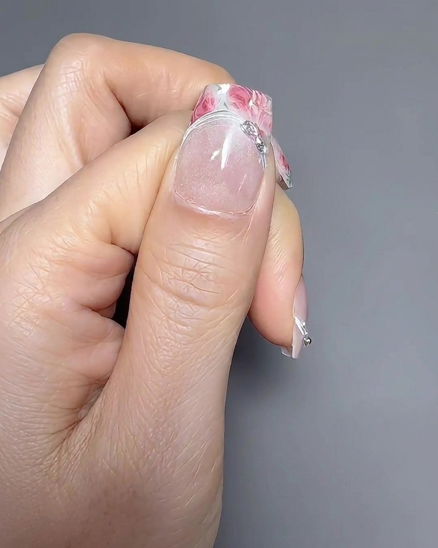 Zbliżenie pędzla do zdobień nakładającego cienką żelową linię wzdłuż linii uśmiechu manicure francuskiego.