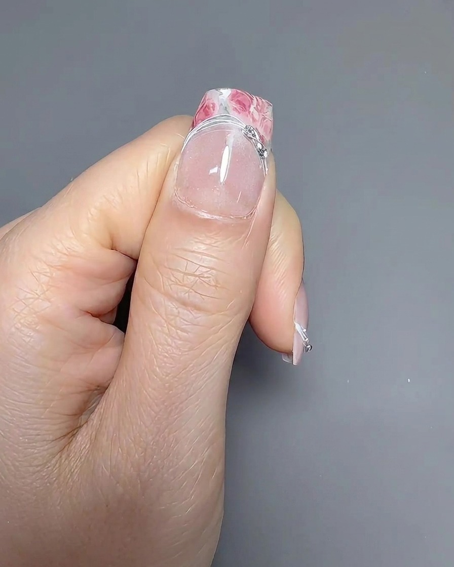 Cienki pędzelek do zdobień ostrożnie rysujący linię uśmiechu na paznokciu z manicure francuskim.