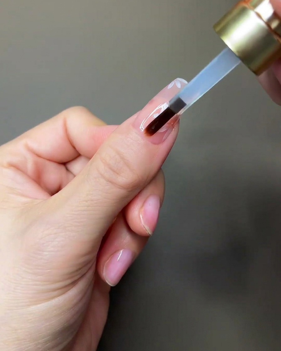 Dłoń umieszczająca paznokieć pod małą przenośną lampą UV/LED w celu utwardzenia.