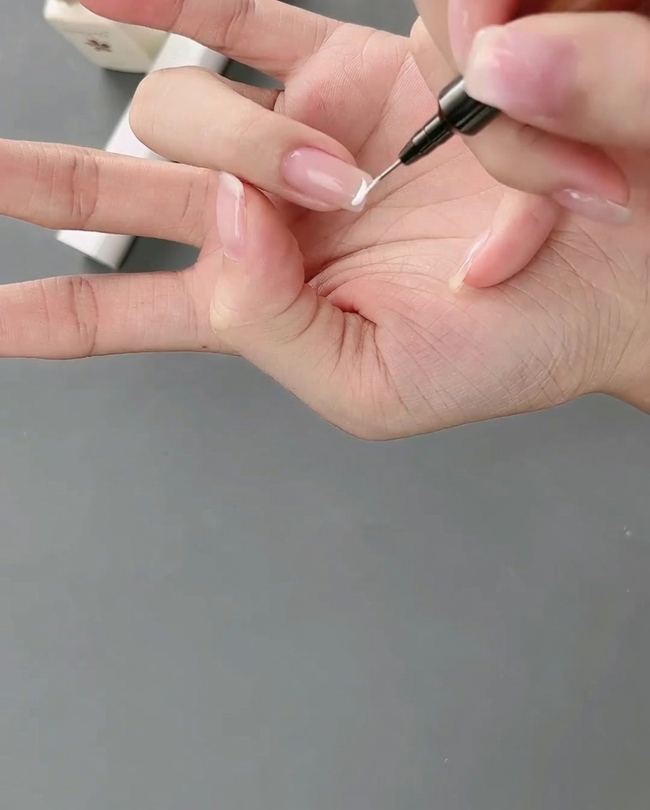 Pędzelek typu liner aplikujący precyzyjną białą linię tworzącą wysoko osadzoną końcówkę french.