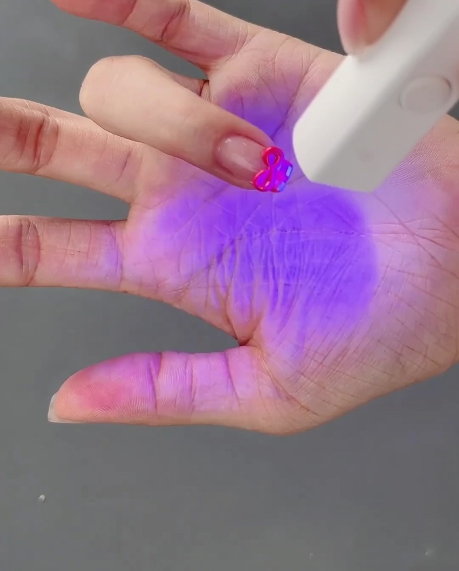 Dłoń z gotową kokardką 3D utwardzaną pod lampą UV.