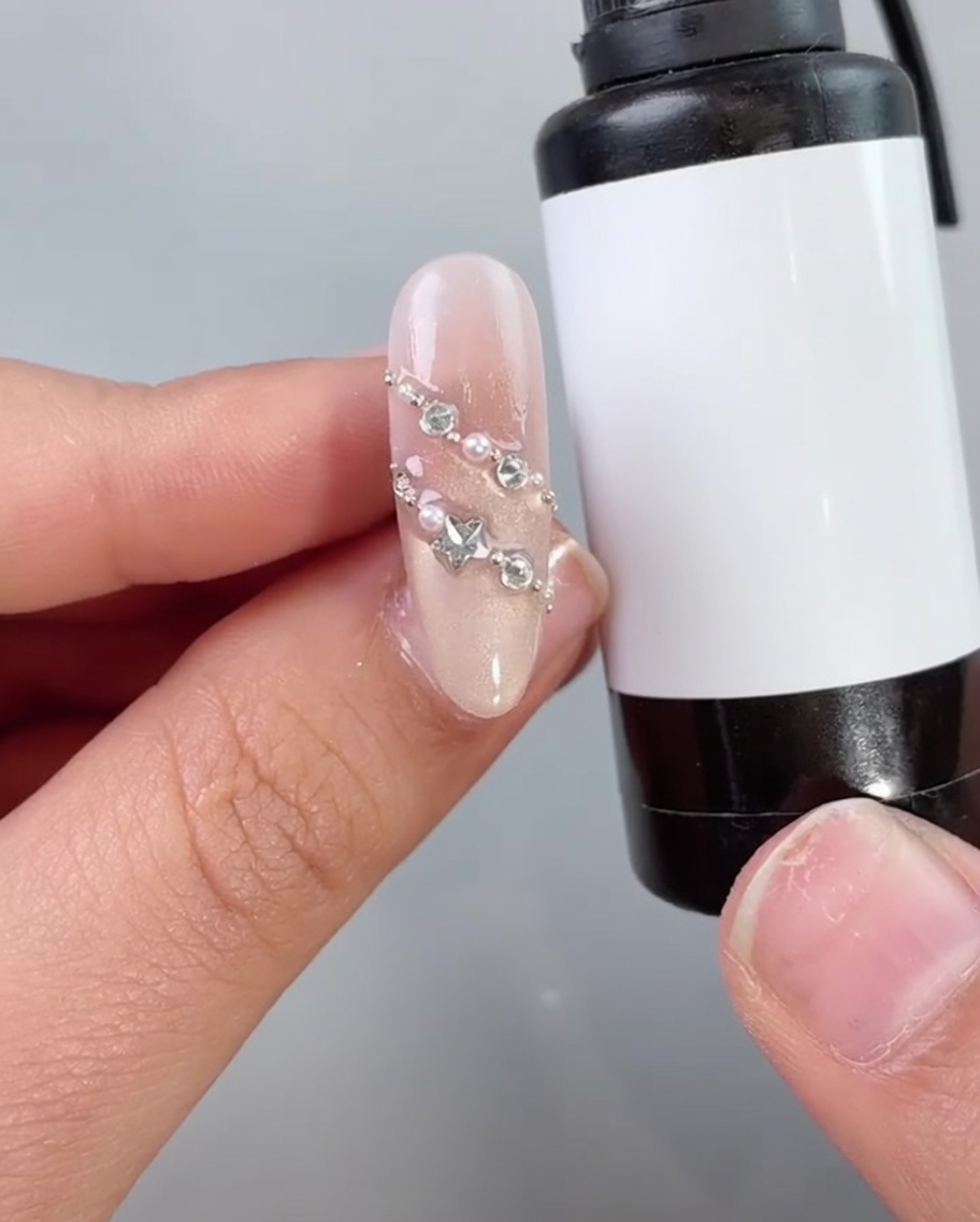 Pędzelek aplikujący top coat na zdobienie z perełkami i cyrkoniami.