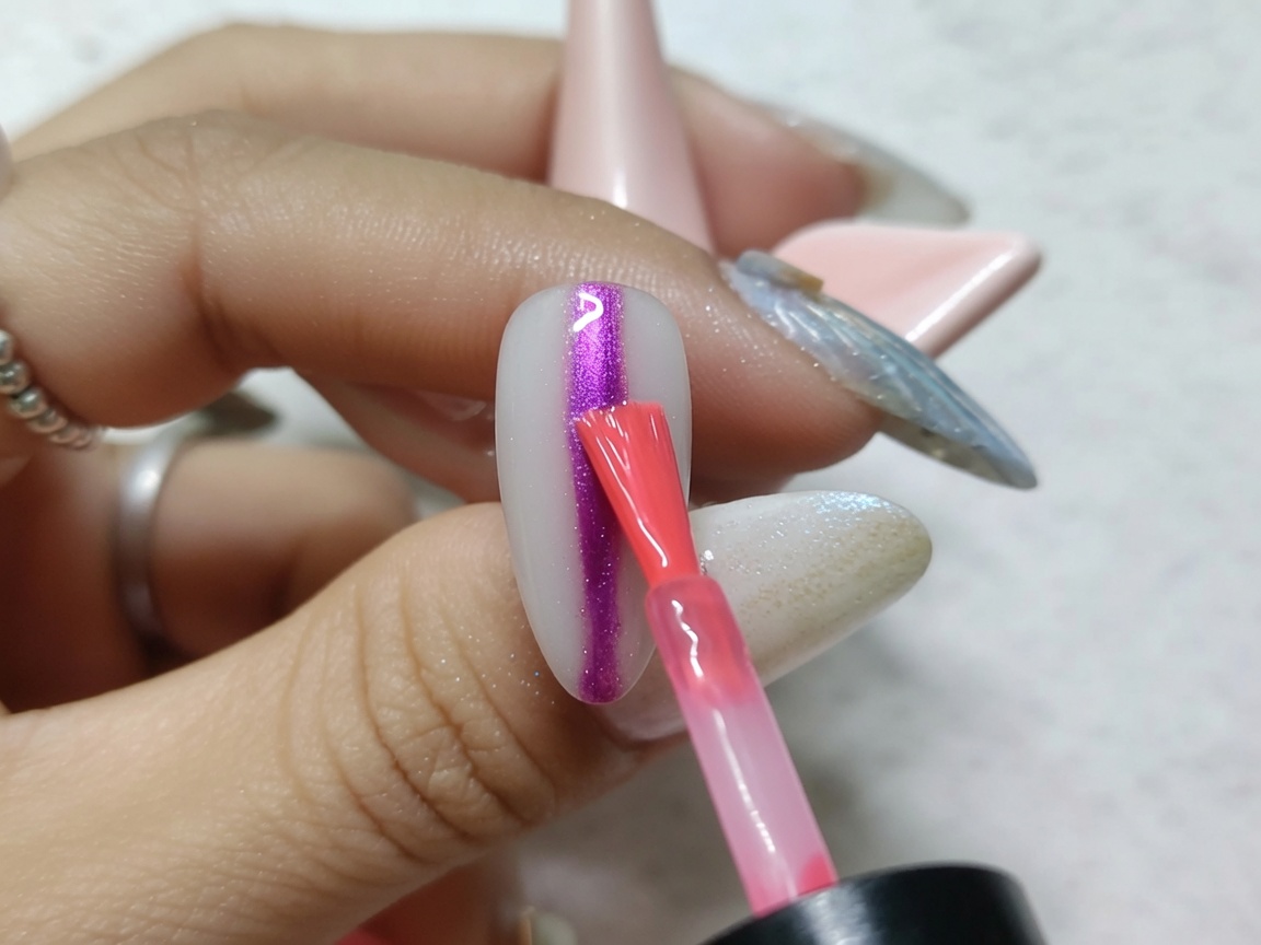 Pędzelek do nail artu malujący pionowy pasek jaskrawoczerwonego tuszu akwarelowego przez środek paznokcia.