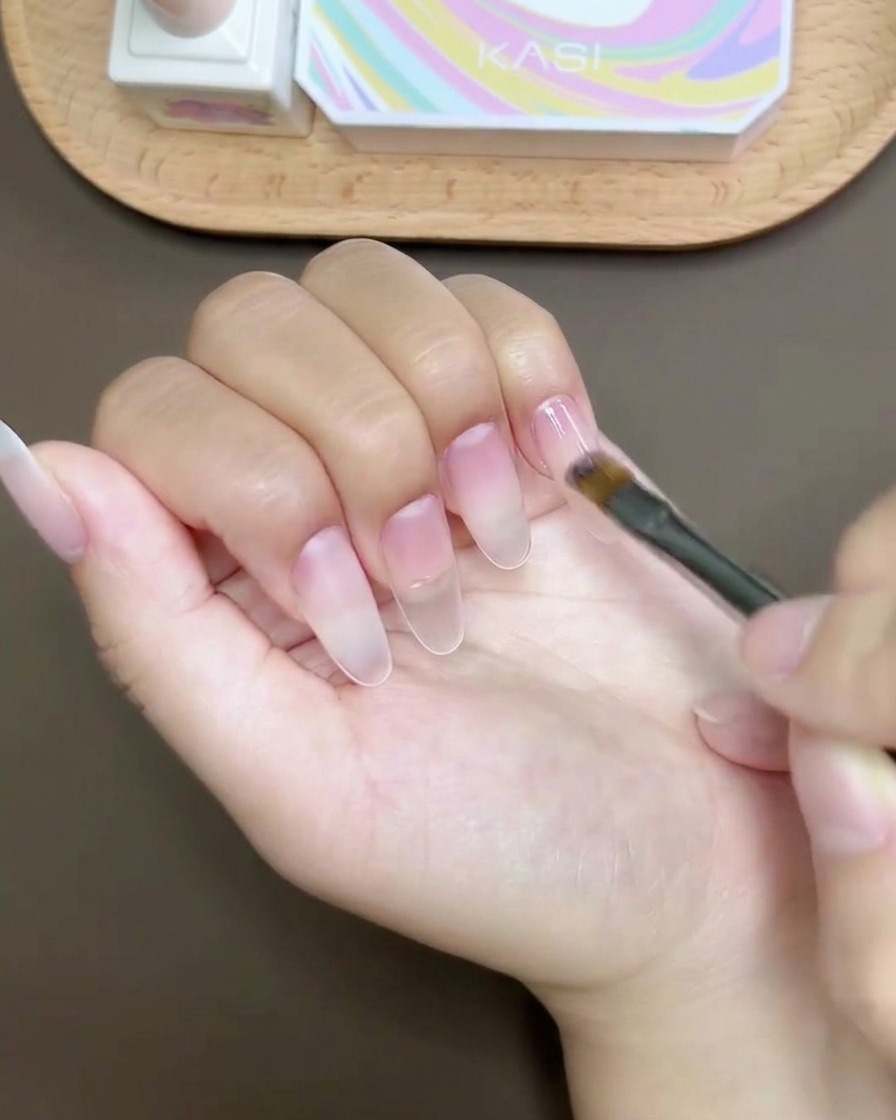 Pędzelek z żelem nakładający lśniącą warstwę wykończeniową na gotowy manicure.