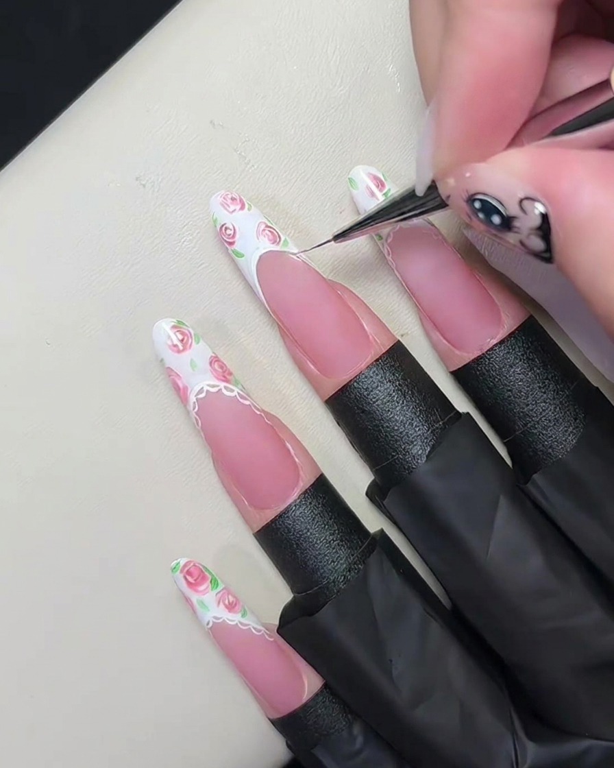 Makrofotografia cienkiego pędzelka rysującego cienką białą linię wzdłuż linii uśmiechu manicure francuskiego.