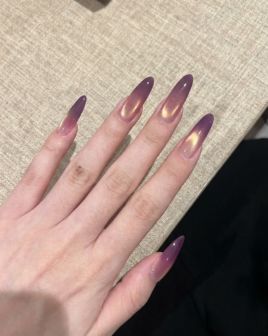 Dłoń z gotowymi fioletowo-złotymi paznokciami cat-eye utwardzanymi w lampie UV.