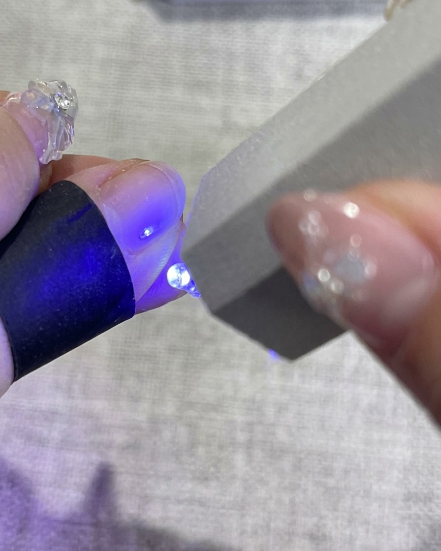 Dłoń z kwiatowym manicure w lampie UV podczas utwardzania.