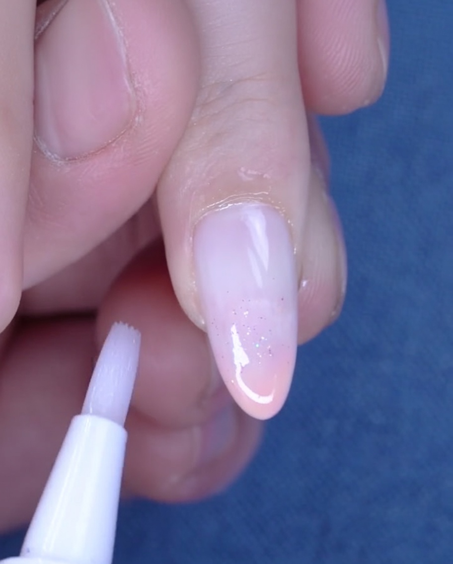 Pisak z oliwką do skórek używany do nawilżania skóry wokół świeżo wykonanego manicure.