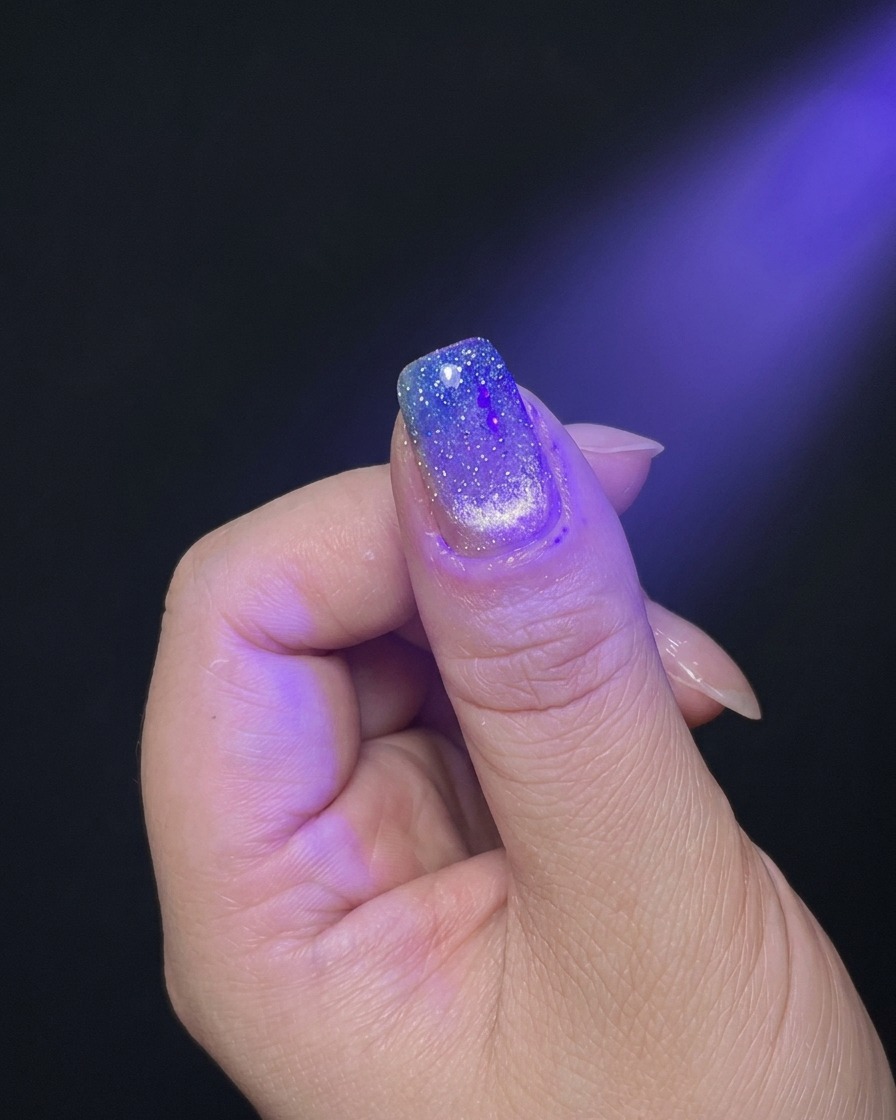 Dłoń pod purpurowym światłem lampy UV/LED podczas utwardzania.