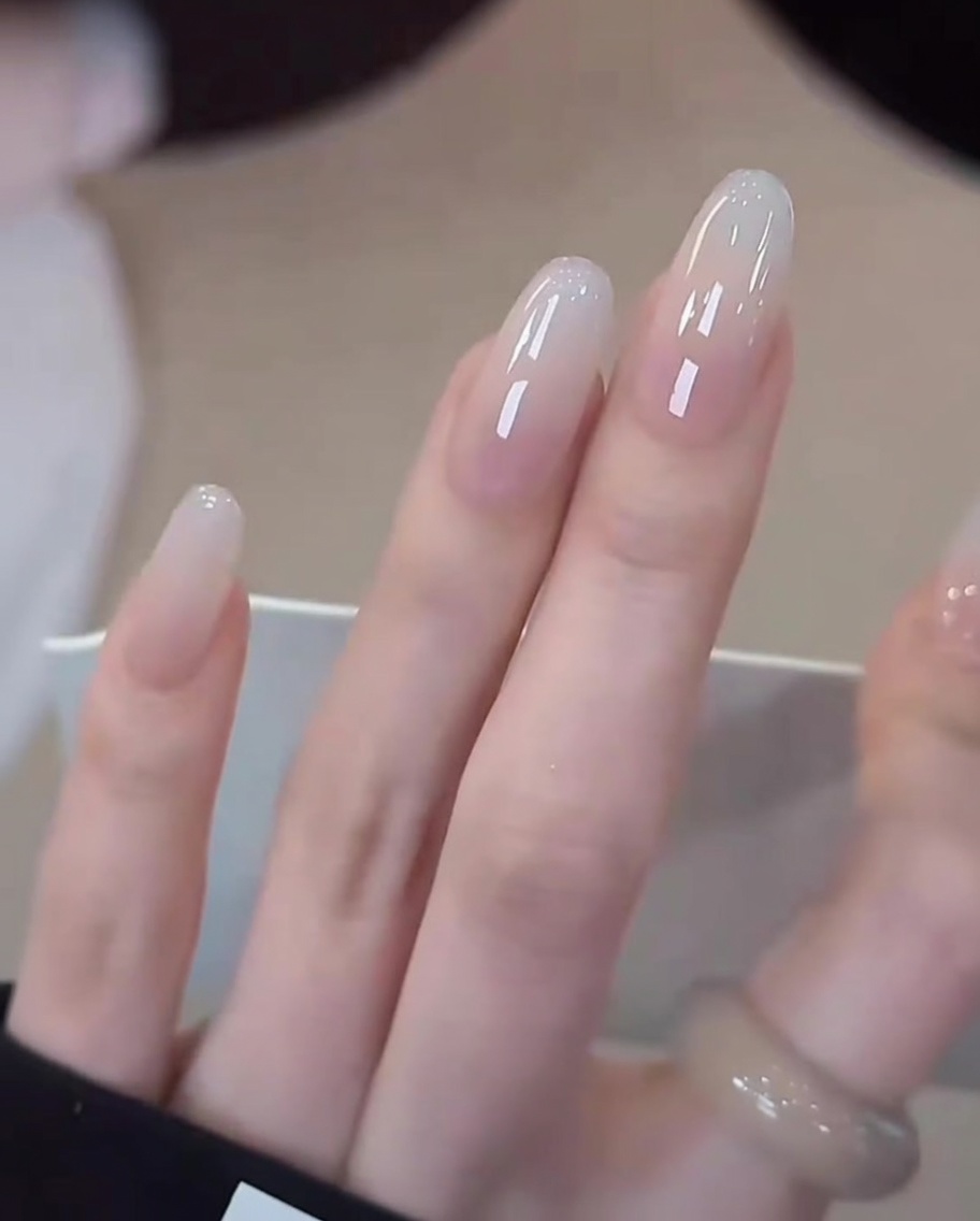 Zbliżenie dłoni z gotowym manicure w lampie UV/LED podczas ostatniego utwardzania.