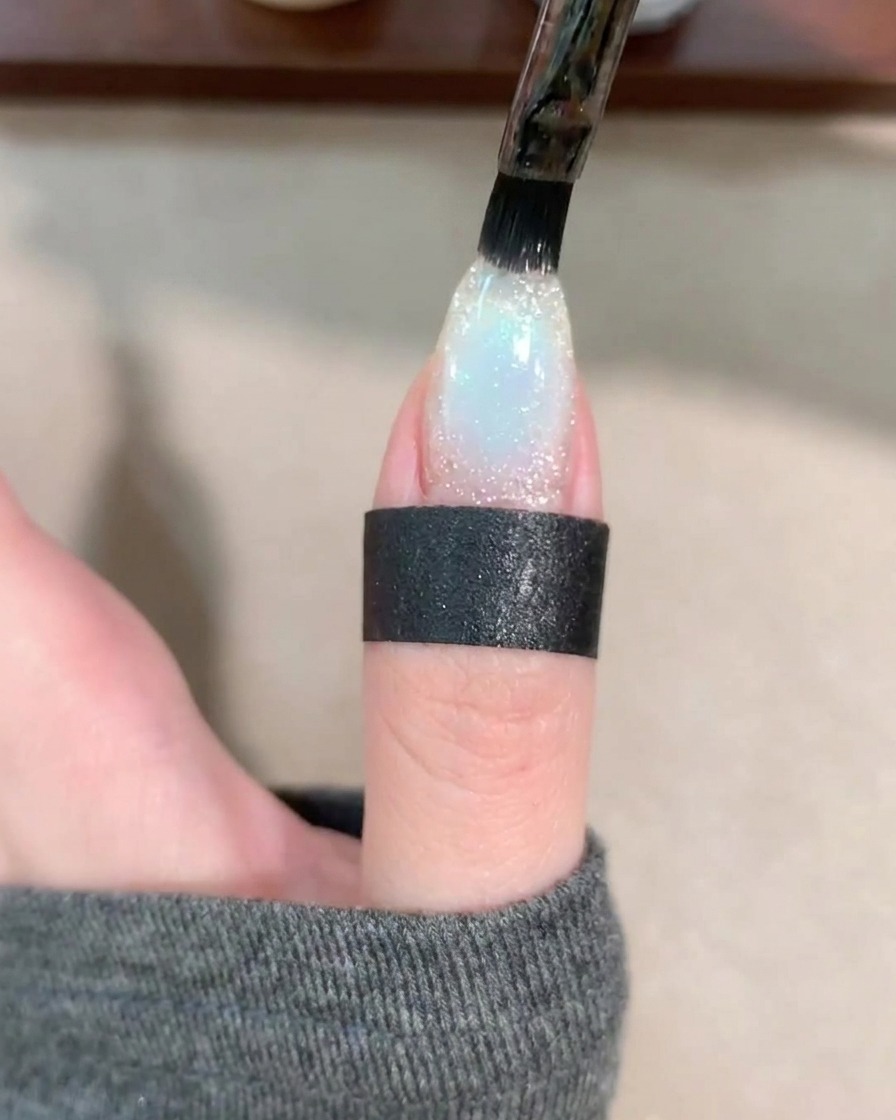 Pędzelek do żelu nakładający przejrzystą warstwę bazy na ozdobiony paznokieć.