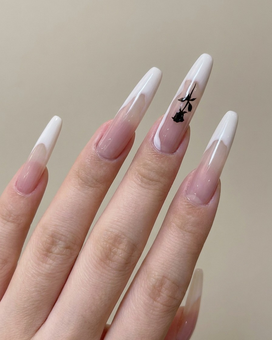 Zbliżenie na pędzelek malujący cienki, czarny wzór gałązki na paznokciu z francuskim manicure.