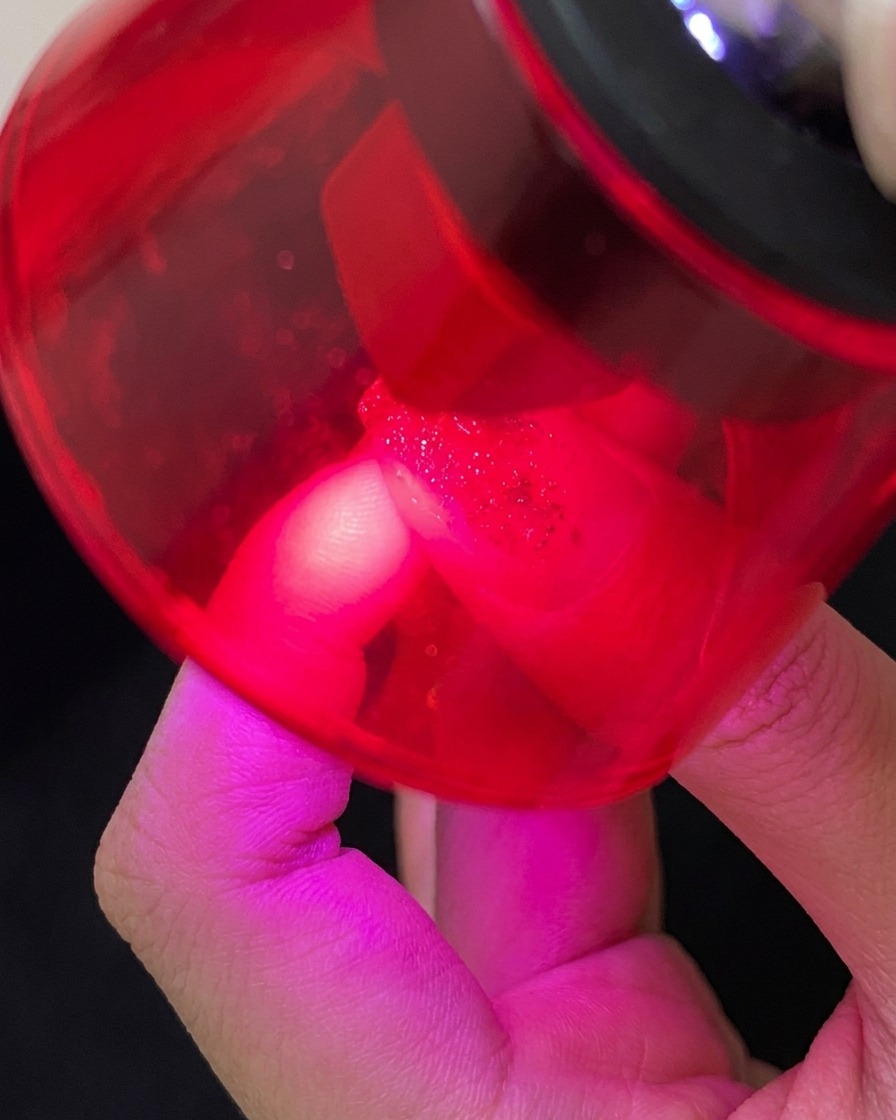 Pędzelek aplikujący nabłyszczający top coat na paznokieć z ozdobami.