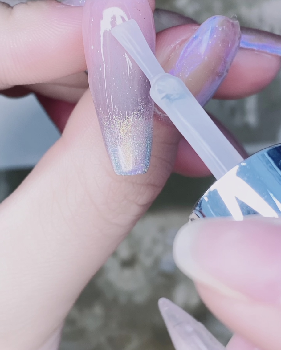 Pędzelek nakładający przezroczysty top coat na pyłek w formie gradientu.