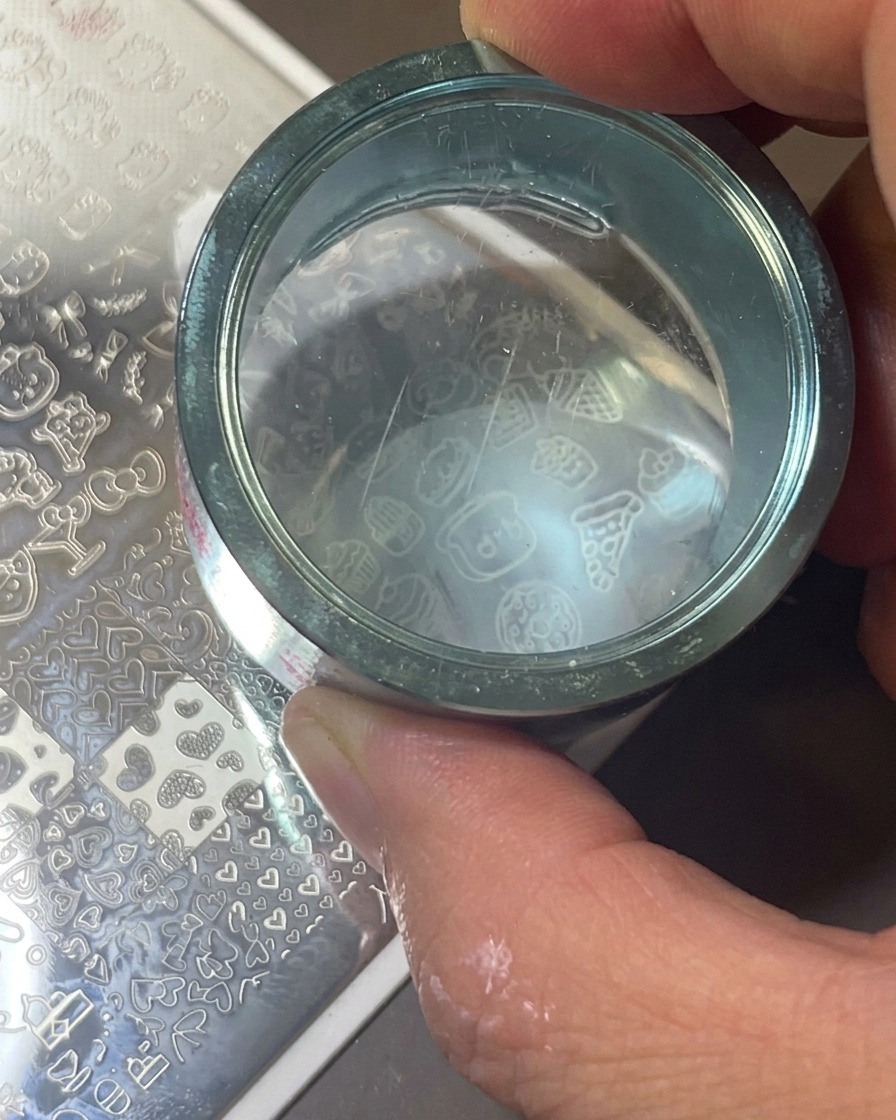 Przezroczysty silikonowy stempel dociskany do metalowej płytki w celu pobrania białego wzoru.