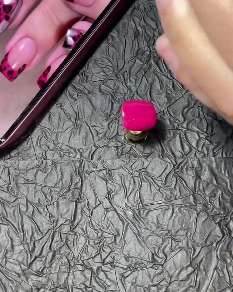 Tips z manicure zanurzany i obracany w małym pojemniczku z przezroczystym proszkiem akrylowym.