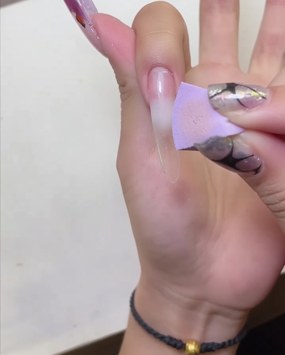 Dłoń umieszczona pod lampą LED do paznokci w celu utwardzenia nałożonej bazy peel-off.