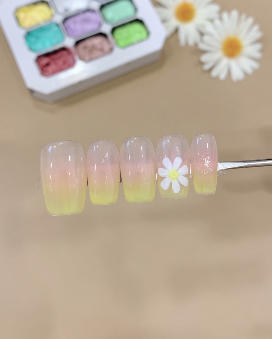 Gąbka dociskająca różowy i żółty żel na tipsa, tworząc miękki gradient ombre.